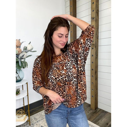 A woman wearing a leopard print top with 3/4 dolman sleeves and round neckline, in a casual setting.