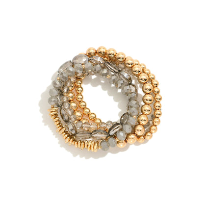 Set of gold and gray beaded bracelets on a white background